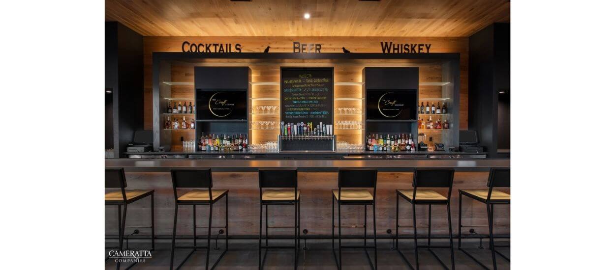 A café counter with bar stools and menu boards labeled “Cocktails” and “Wine.”