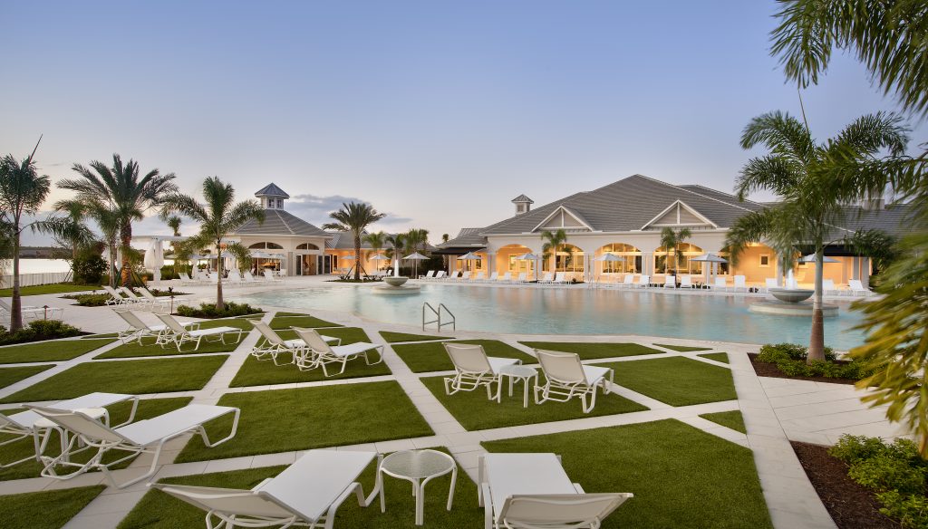 Resort pool area at sunset with lounge chairs, palm trees, and cabanas in the background.