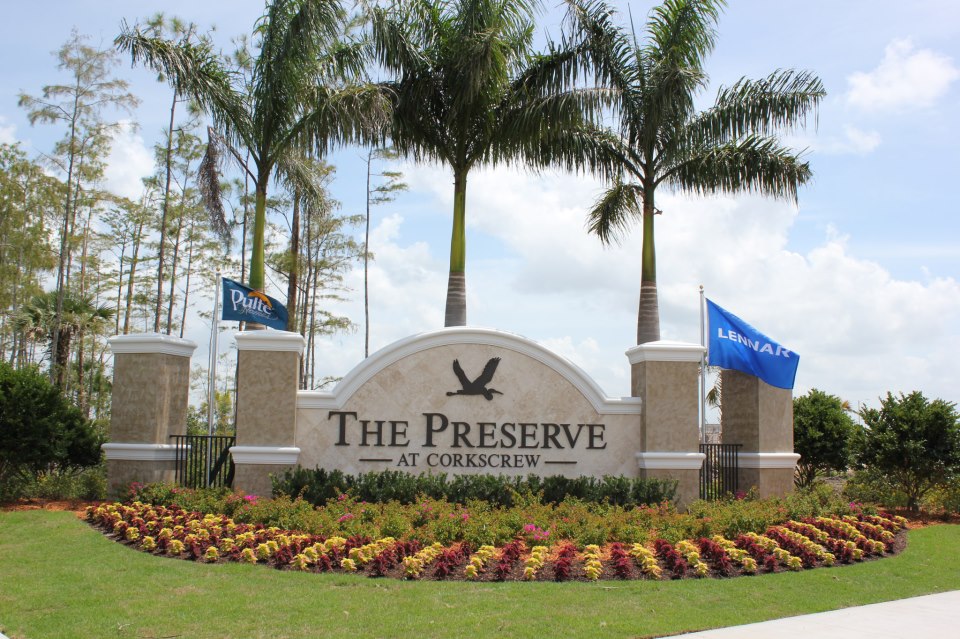 The Preserve at The Preserve at Lenter Crossing entrance sign with flags and palm trees.
