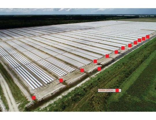 Aerial view of an outdoor solar farm with rows of panels and small red markers along a road.